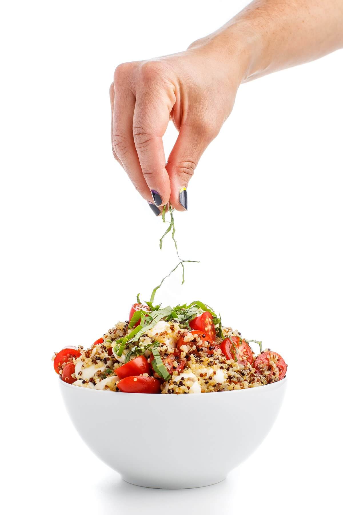 Garnishing caprese quinoa salad with basil.