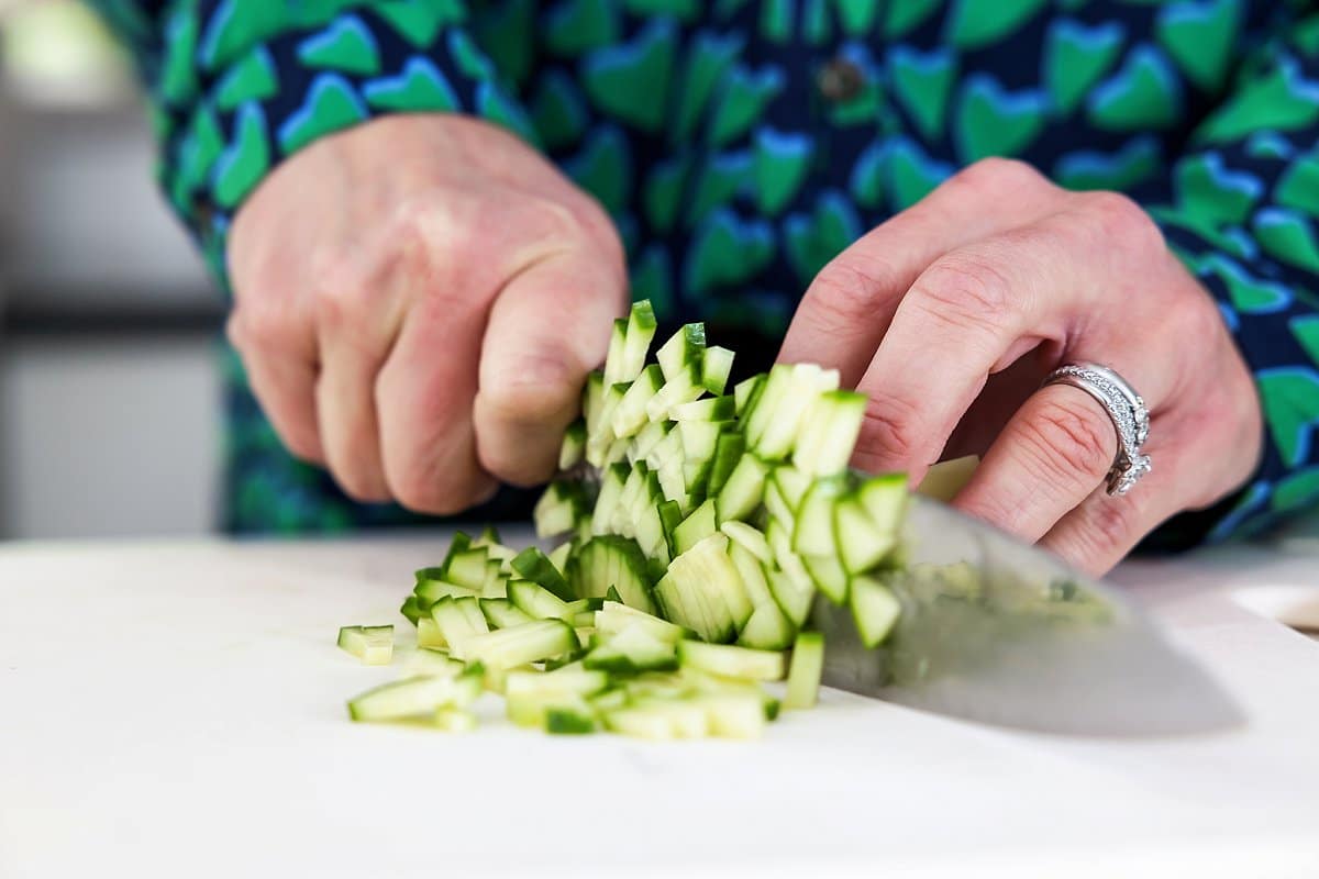 Liz slicing cucumber on a cutting board.