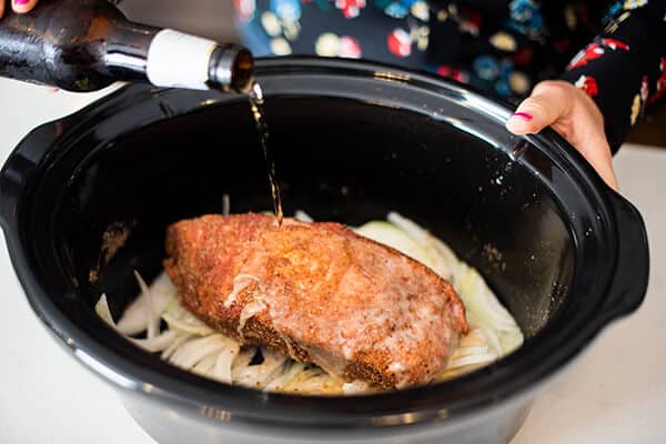 beer being poured onto meat in a crock pot