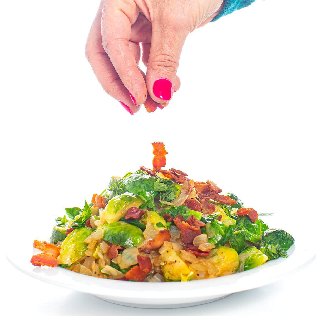 Brussels Sprouts with bacon being sprinkled onto a plate