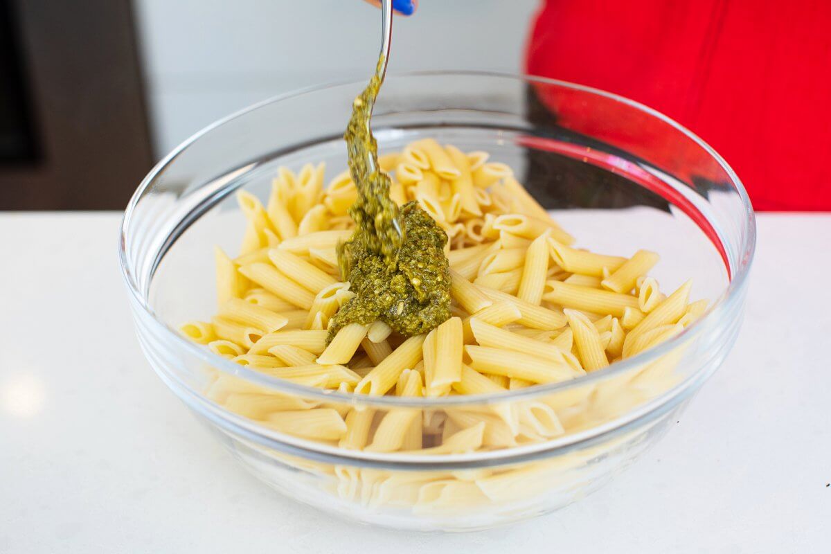 Pesto added to pasta in a bowl