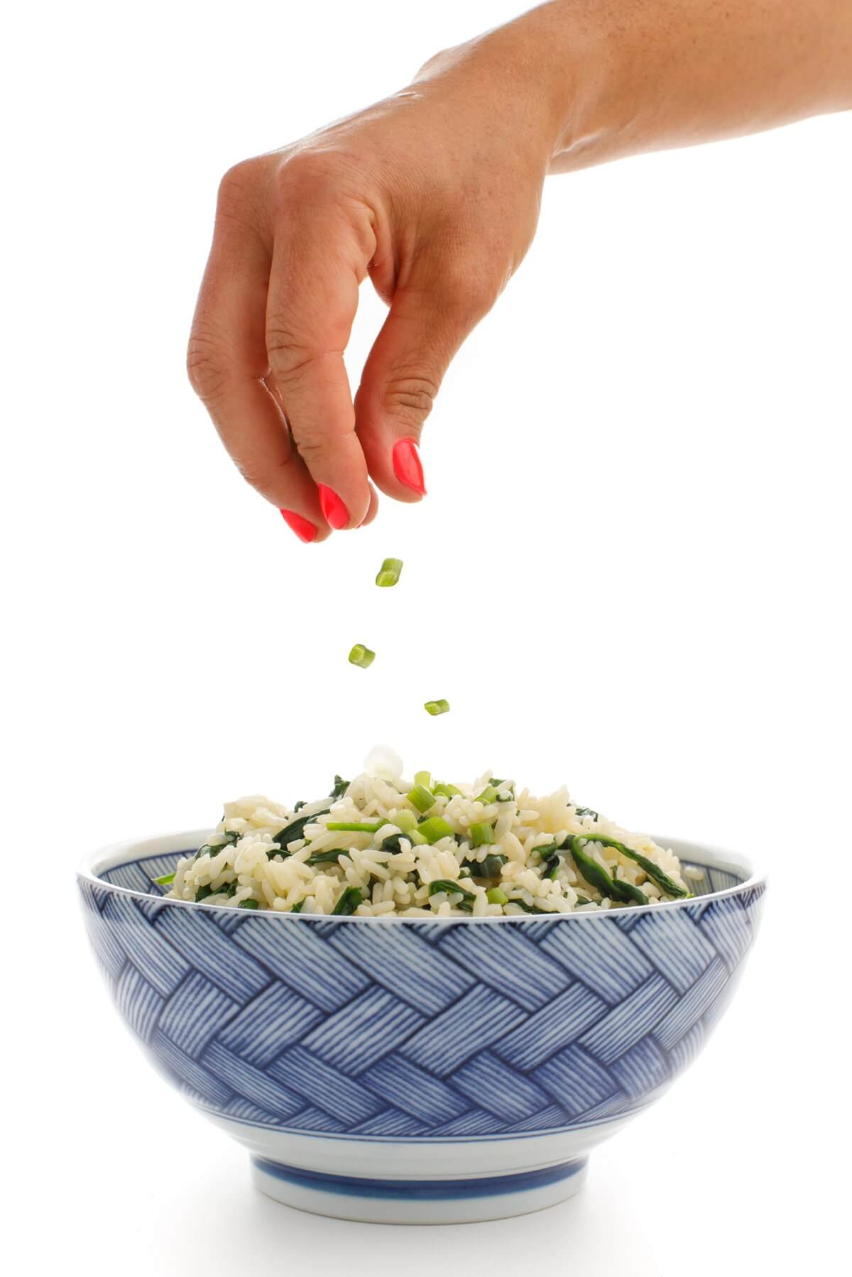 Garnishing Greek spinach rice with chives.