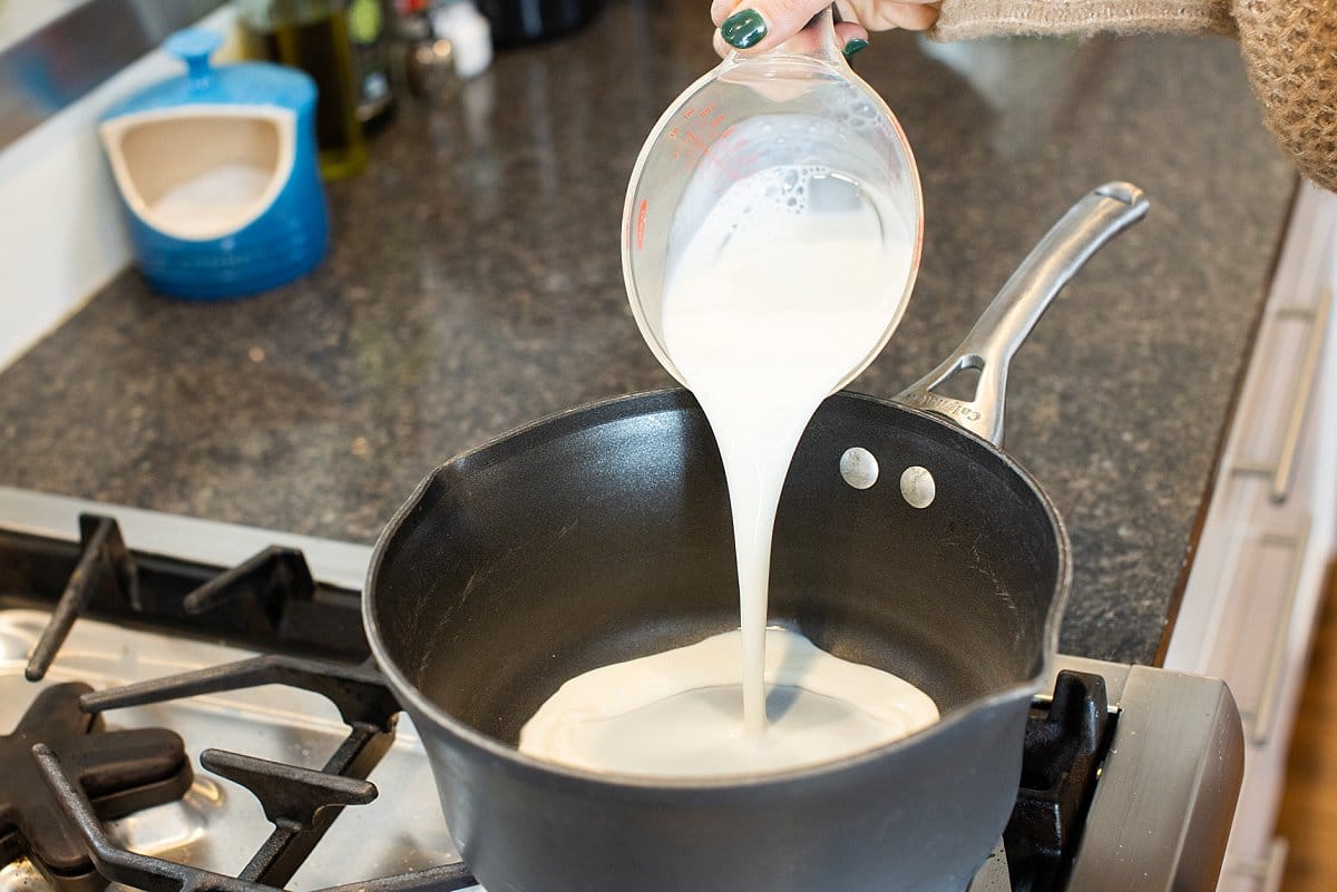 Oatmeal pouring milk into pot