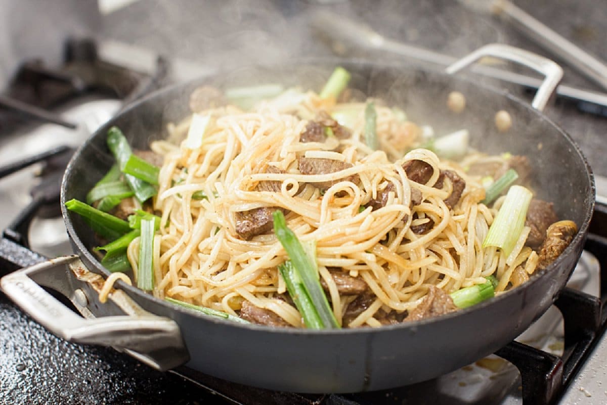 Veggies added to beef stir-fry in skillet.