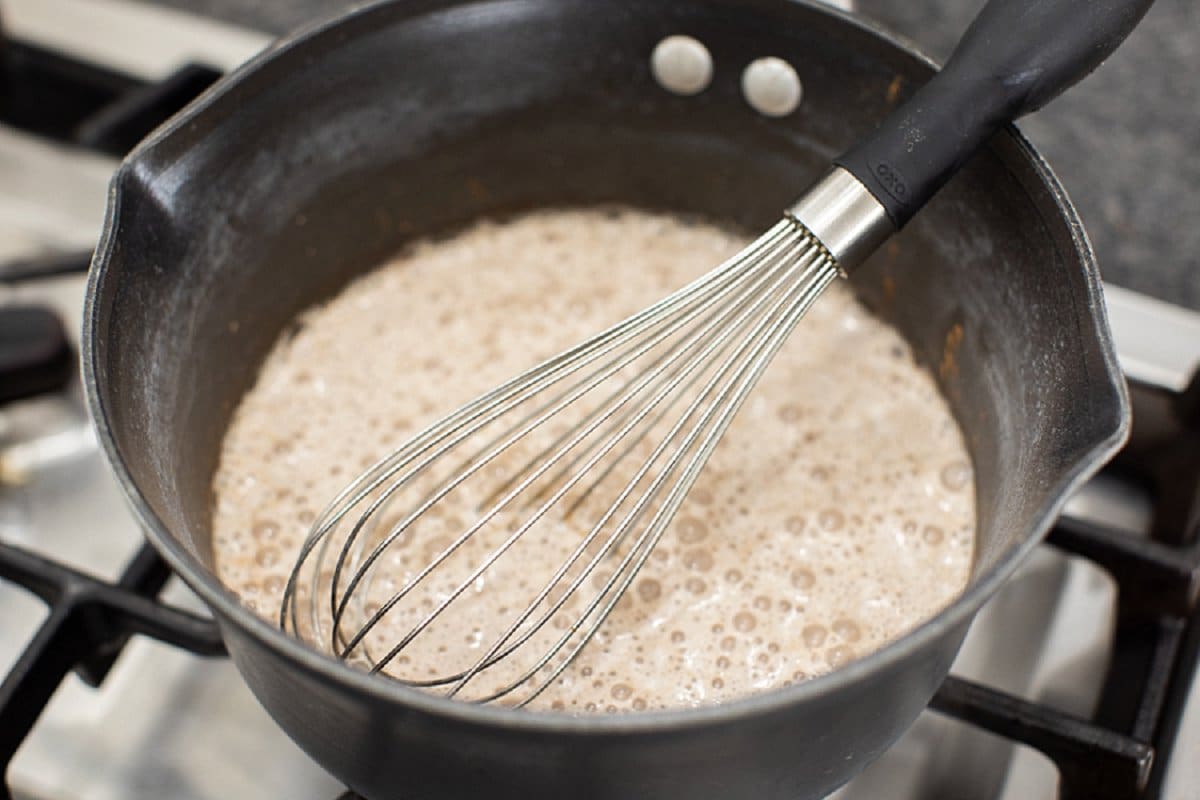 Whisking cocoa powder into milk in pot.