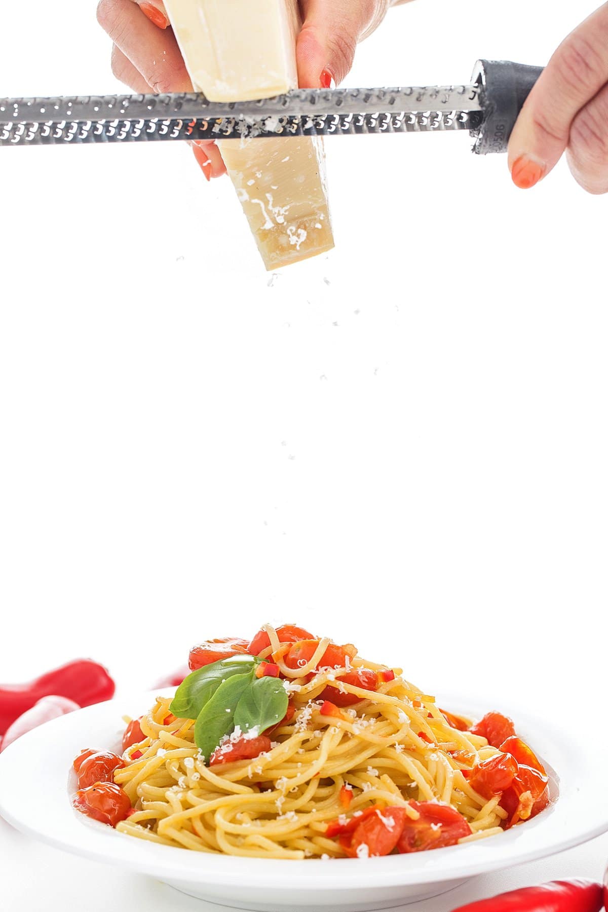 Grating parmesan cheese over spicy pasta with garlic and olive oil