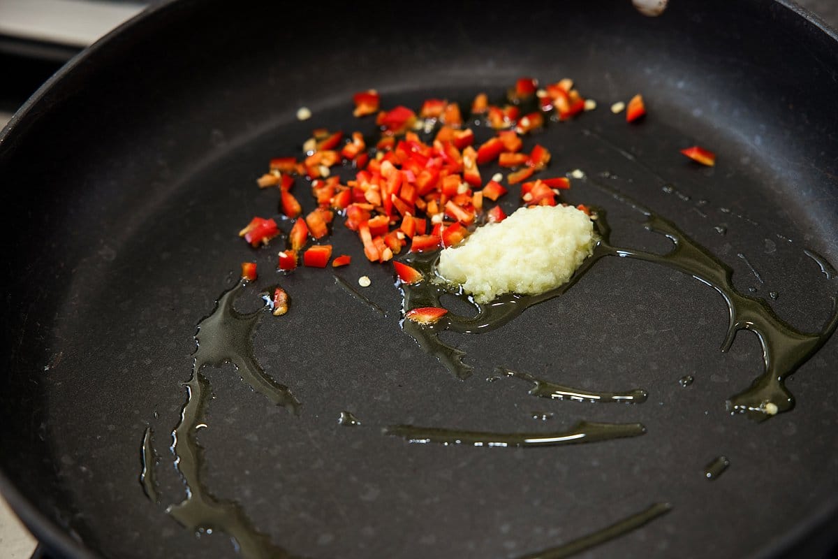 sauteeing red chili peppers in a pan