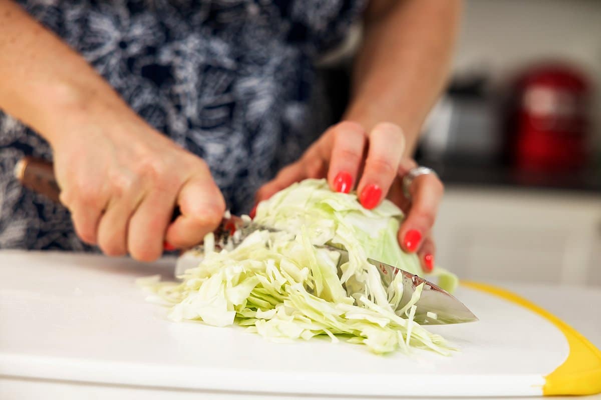 slaw being chopped on a cutting board
