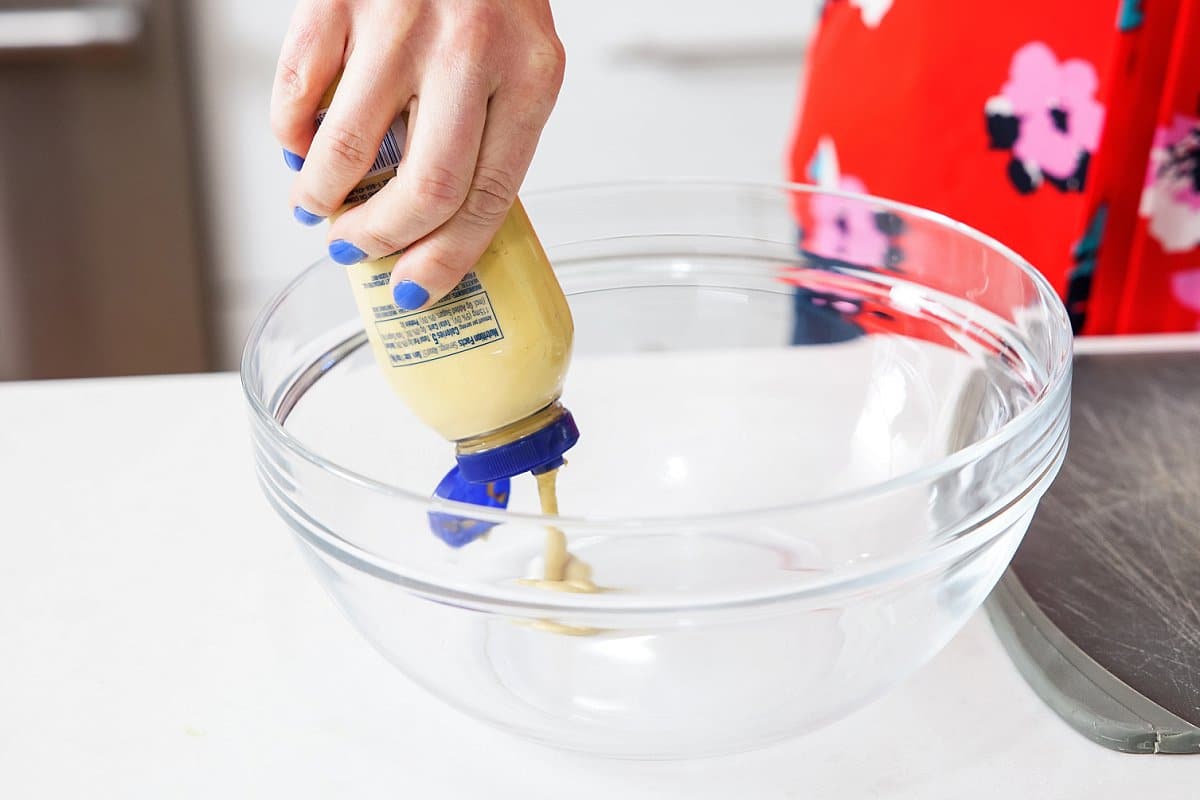 adding mustard to a bowl