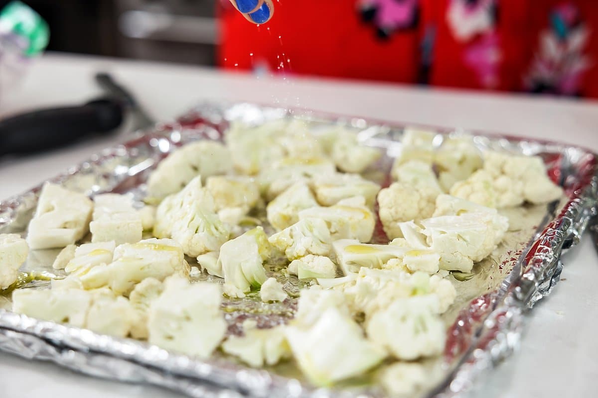 seasoning cauliflower on a baking sheet