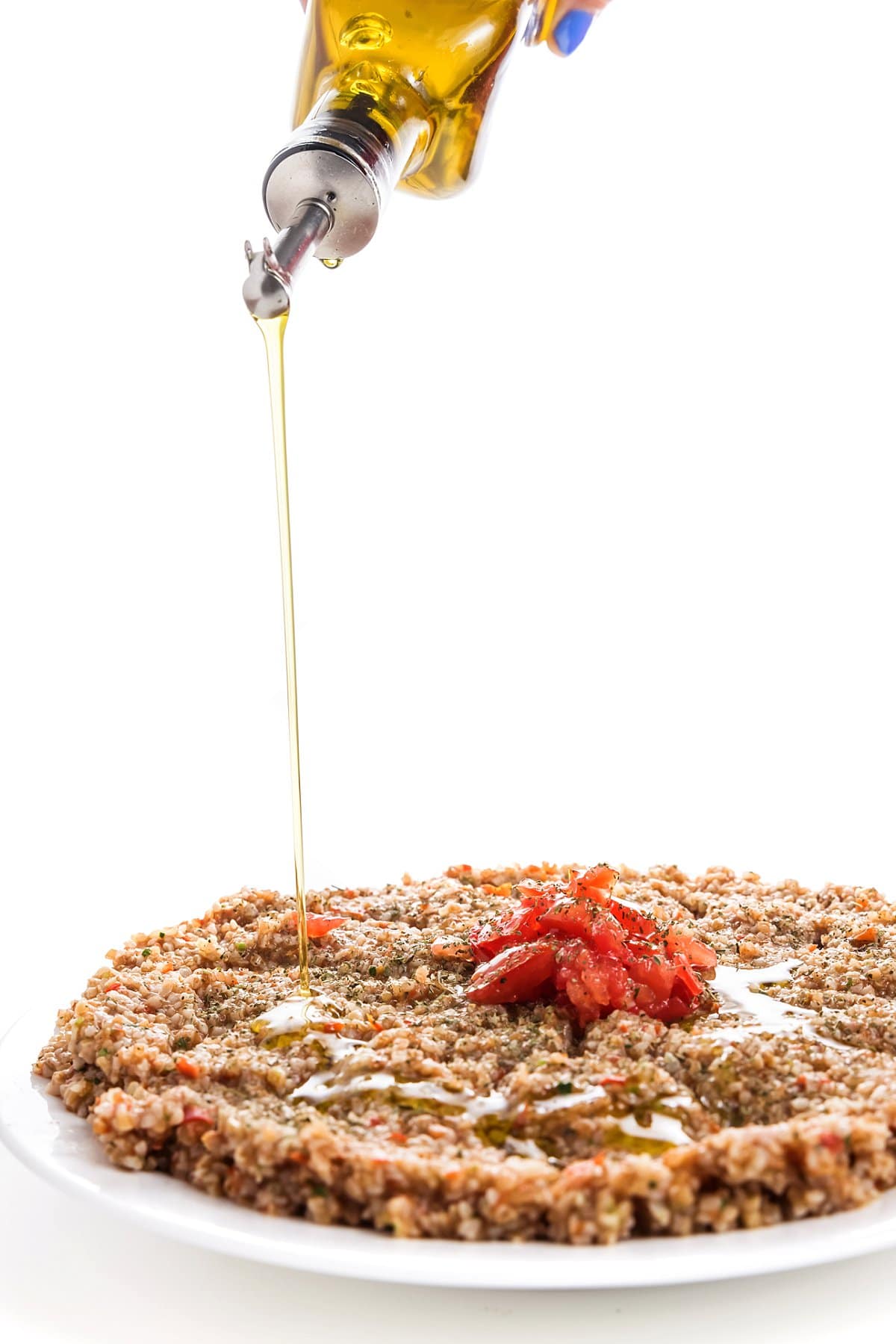 Drizzling olive oil over vegan tomato kibbeh.
