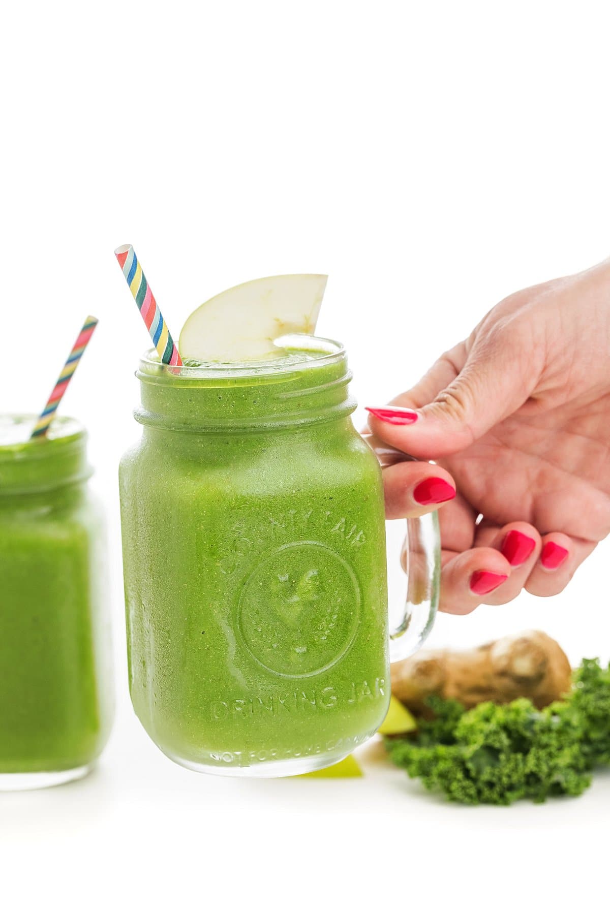 Hand holding pineapple mango green smoothie
