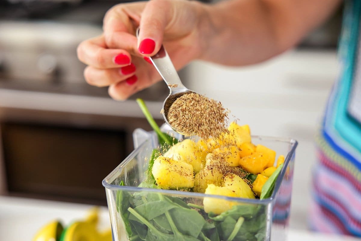 person adding flax seed meal to blender