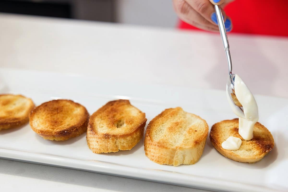 dolloping goat cheese mixture on crostini