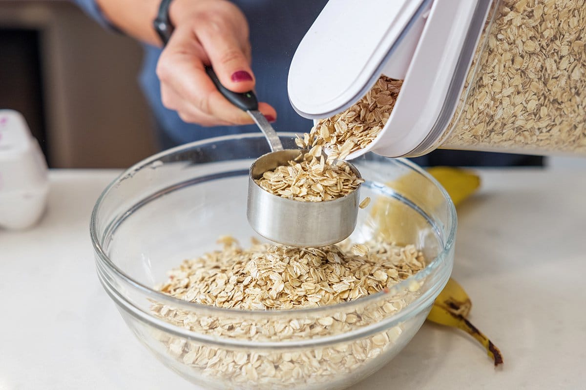 Oats being measured into a glass bowl.