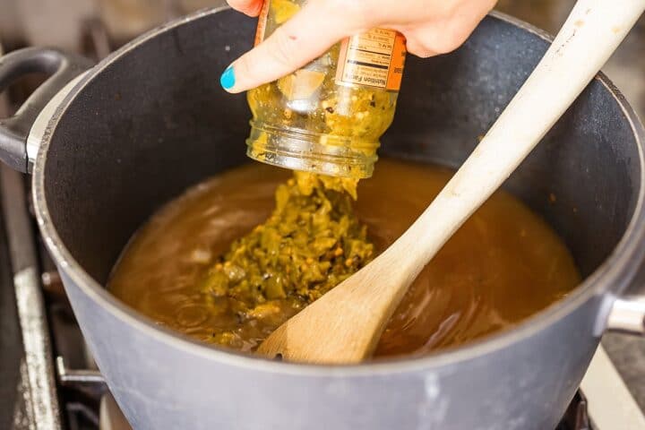 Adding jarred green chilies to stew.