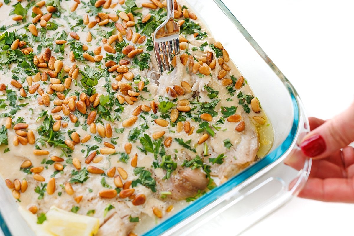 Baked fish with tahini sauce and pine nuts.
