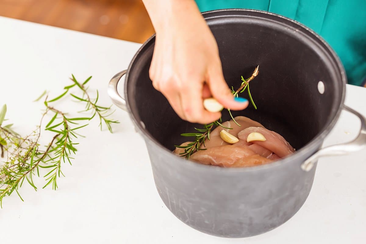 Adding garlic to a pot with chicken breasts.