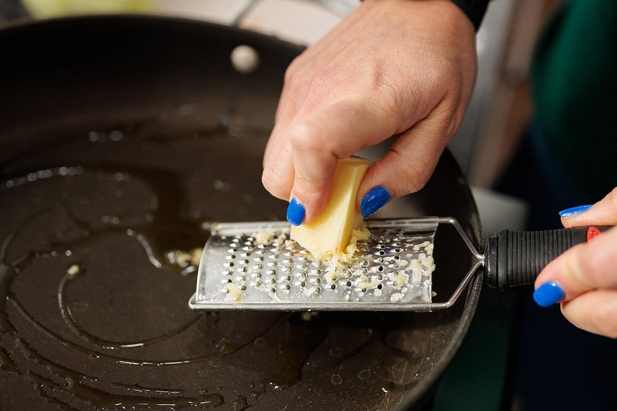 Grating garlic into a pan.