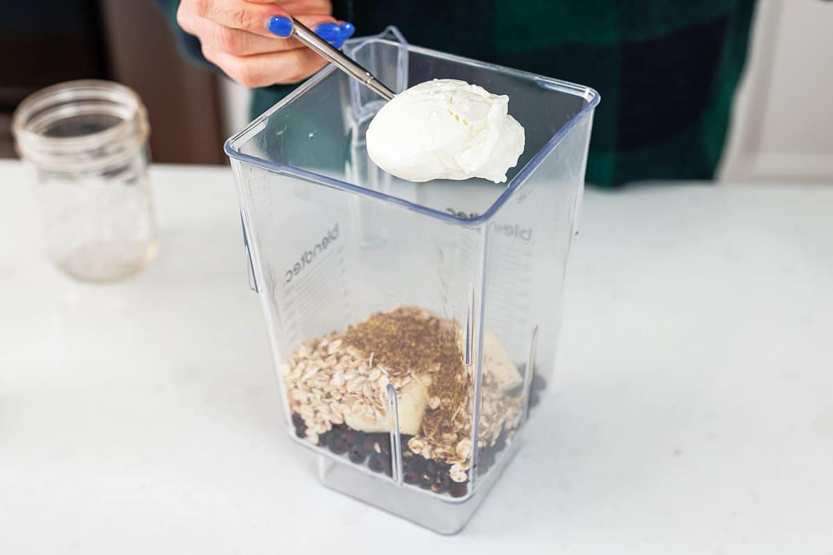 Adding a scoop of yogurt to blender.