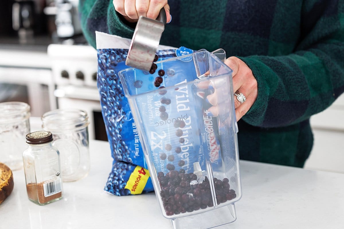 Adding frozen blueberries to blender.