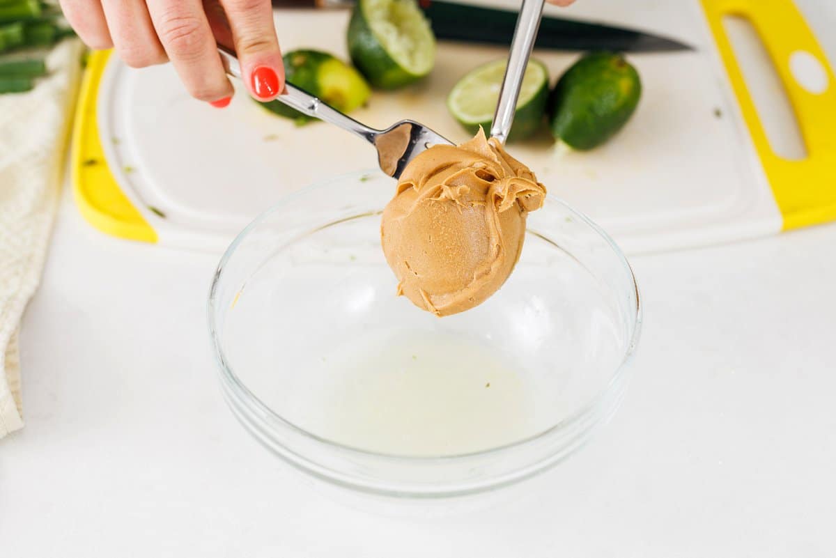 Adding peanut butter to a small glass bowl.