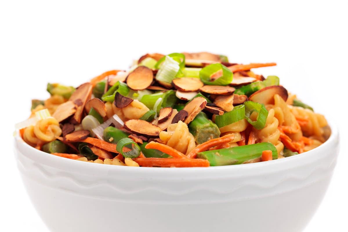 Asparagus pasta salad in a white glass bowl topped with almonds.