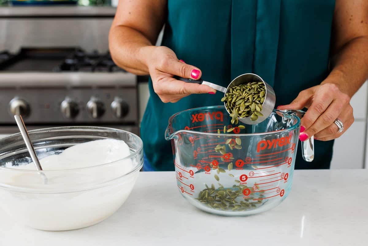 Pouring pumpkin seeds into new bowl.