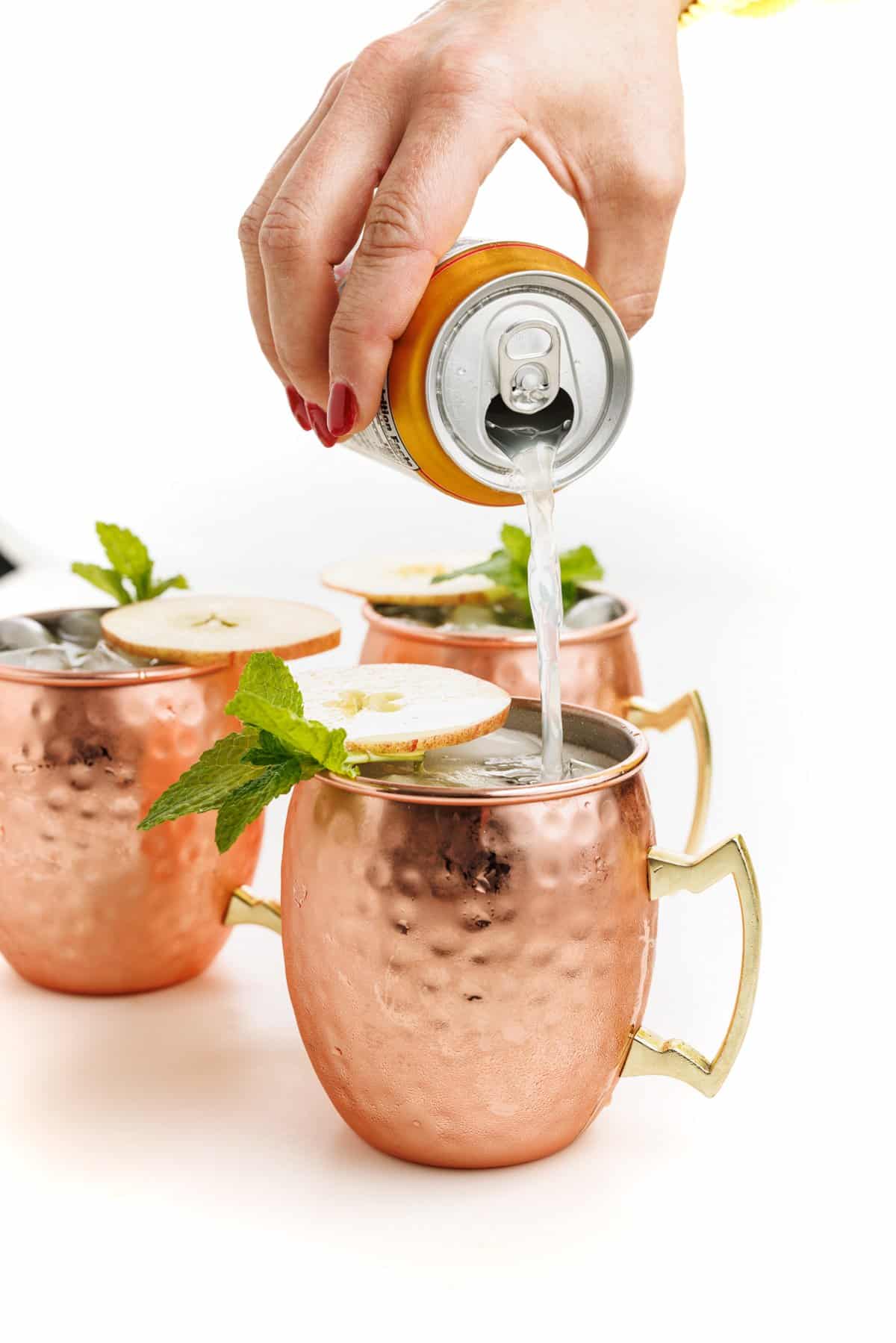 Topping off apple cider Moscow mules with ginger beer.