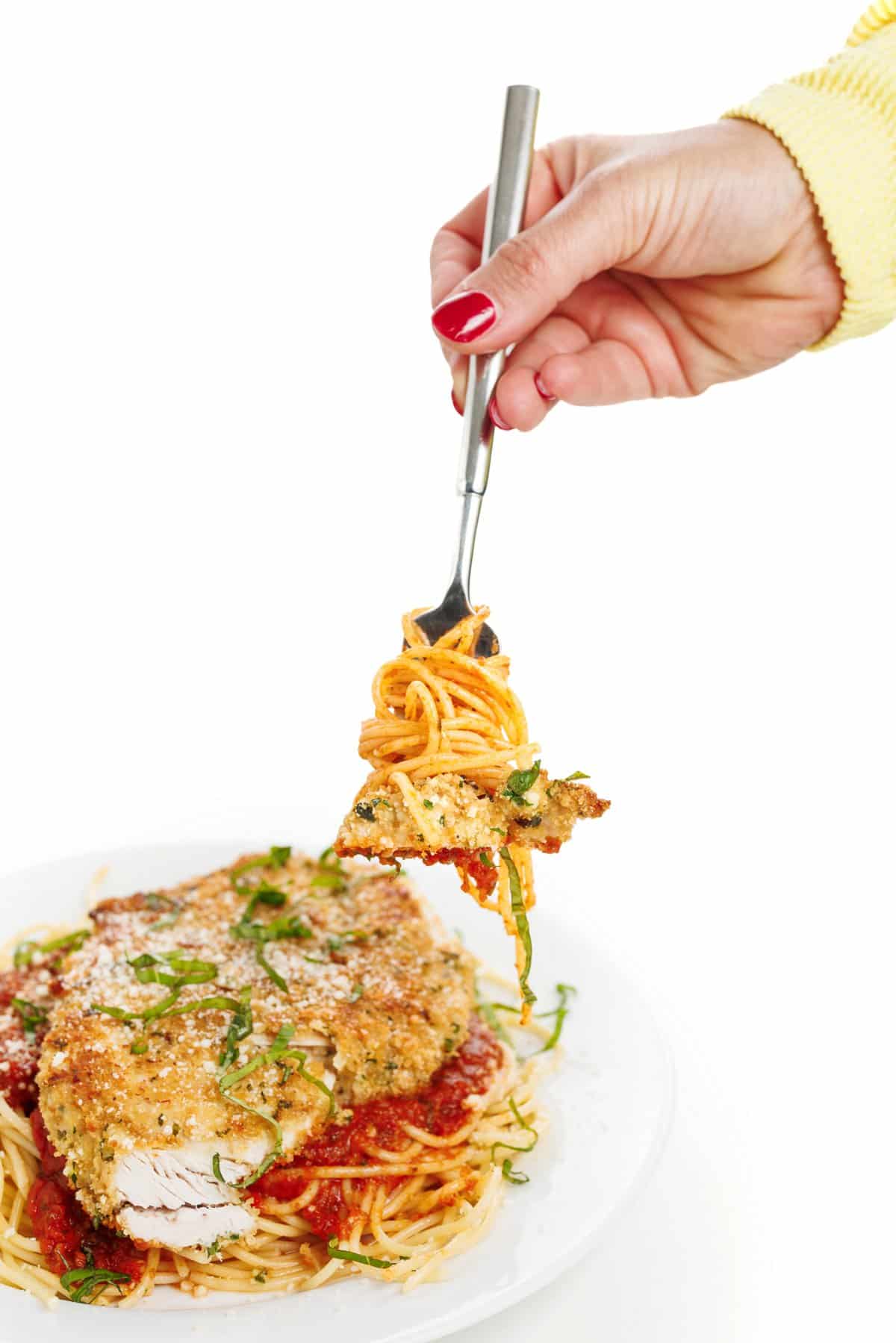 Forkful of oven baked chicken parmesan and spaghetti.