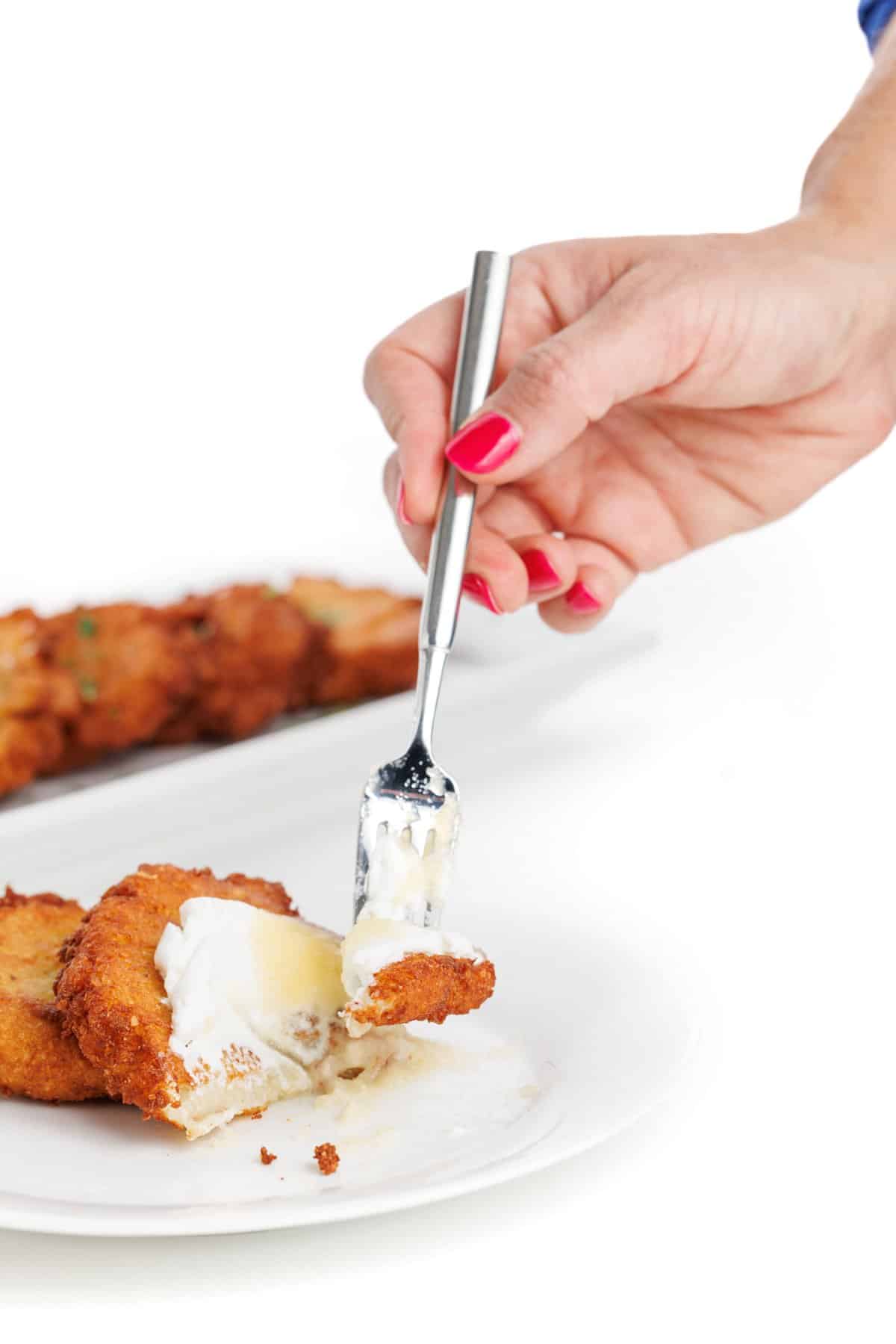 Stabbing traditional potato latke with a fork.