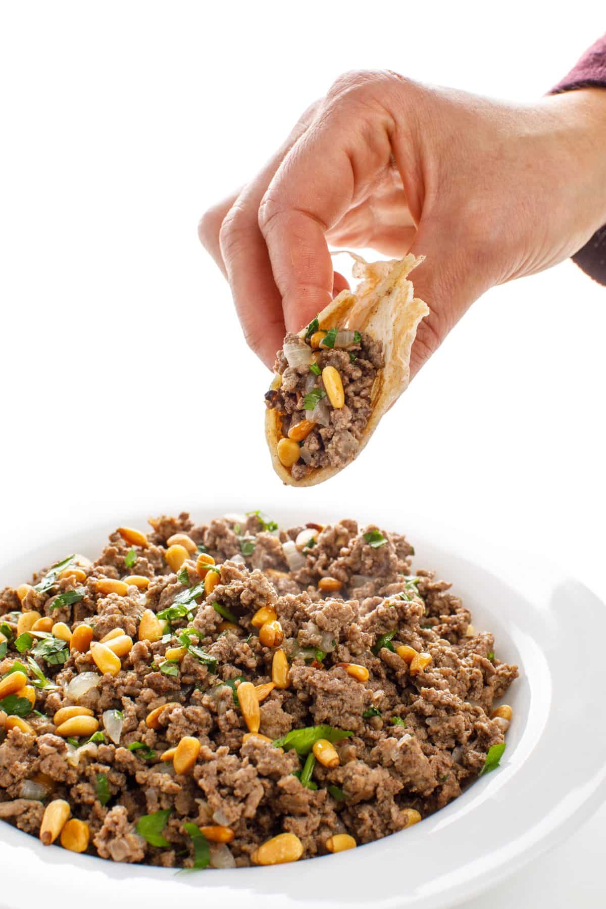 Scooping Lebanese hushwee- ground beef with pine nuts.