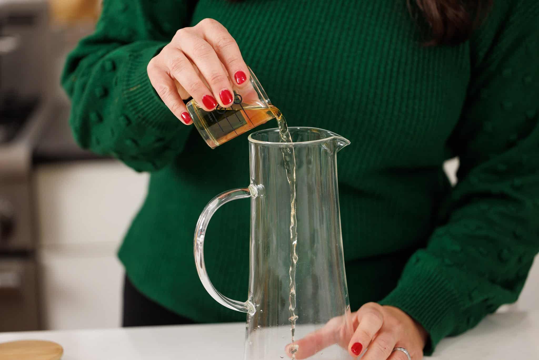 Pouring dark rum into glass pitcher.