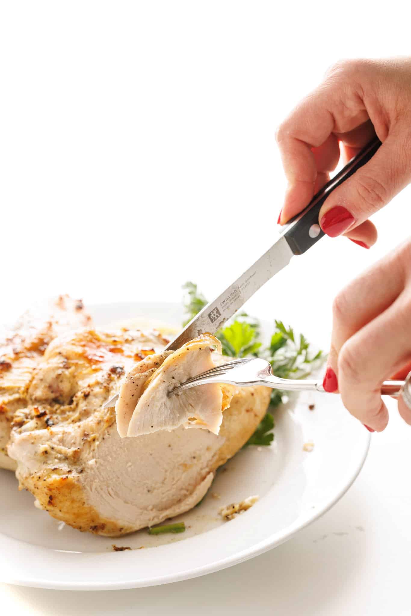 Cutting a bite of lemon pepper baked chicken.
