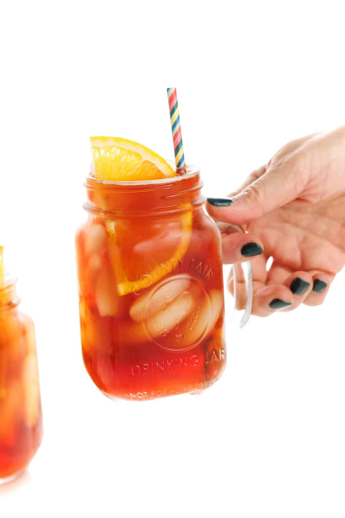 Holding a glass of orange ginger tea iced.