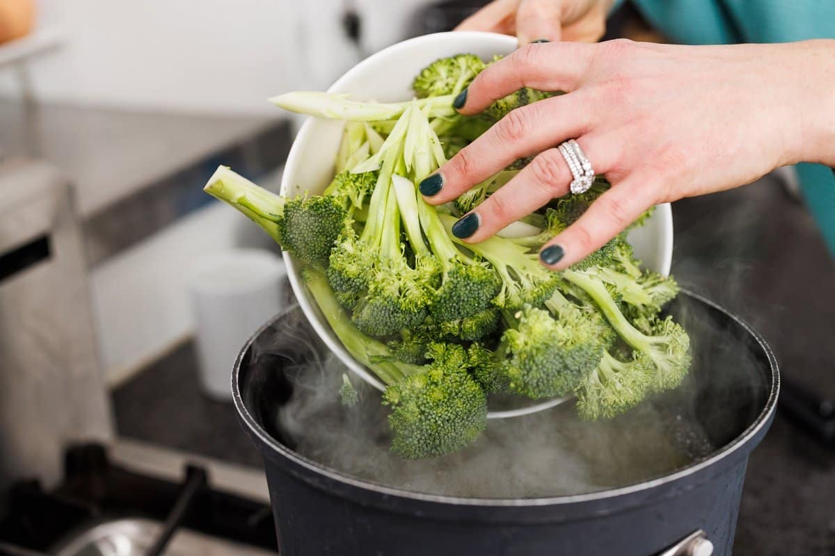 Adding broccoli florets to boiling water.
