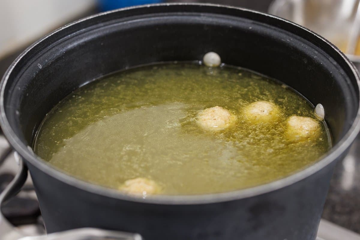 Adding formed matzo balls to soup.