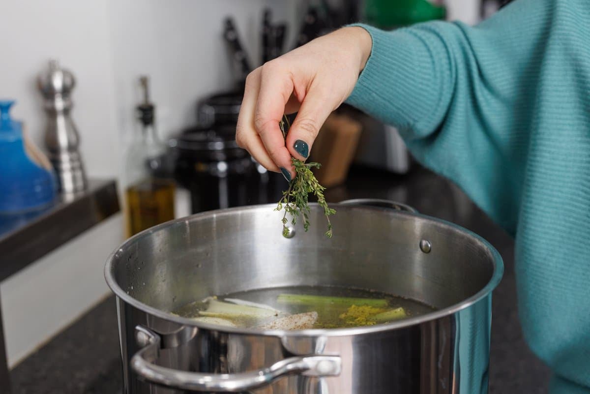 Adding fresh thyme to stock pot.