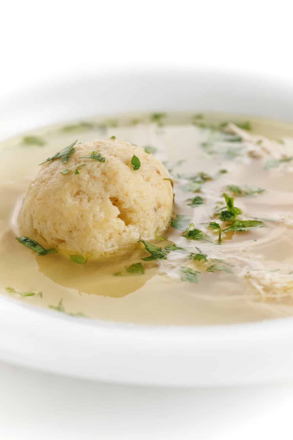 Classic matzo ball soup in a bowl with shredded chicken.