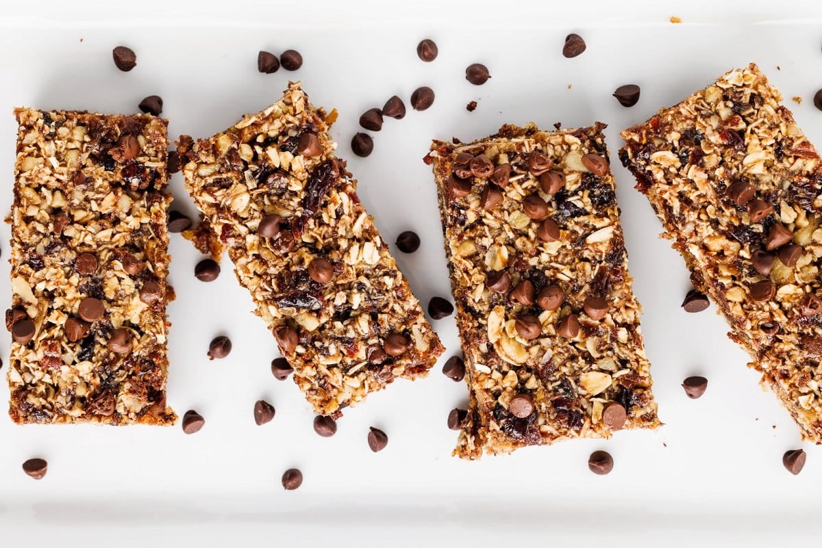 Four seedy oat and flax granola bars in a row on a white platter.