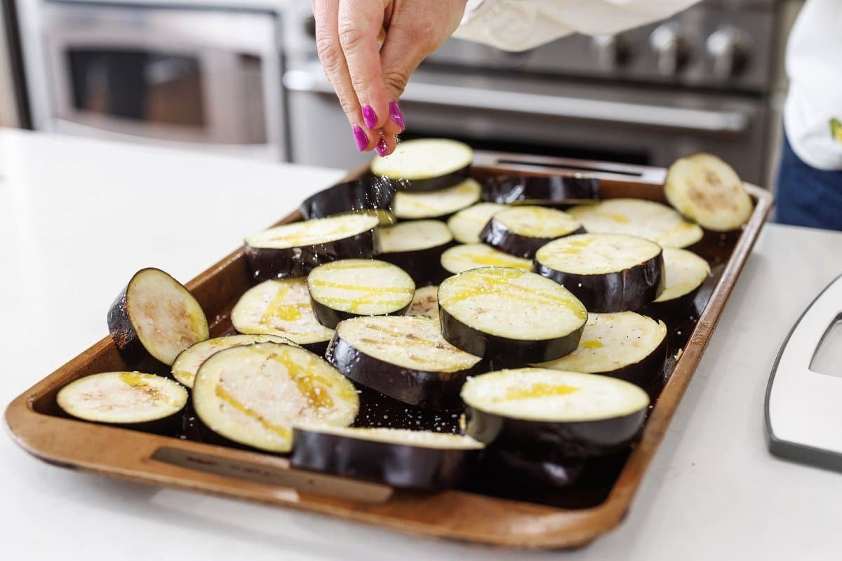 Eggplant slices on a baking sheet drizzled in olive oil and sprinkled with salt.