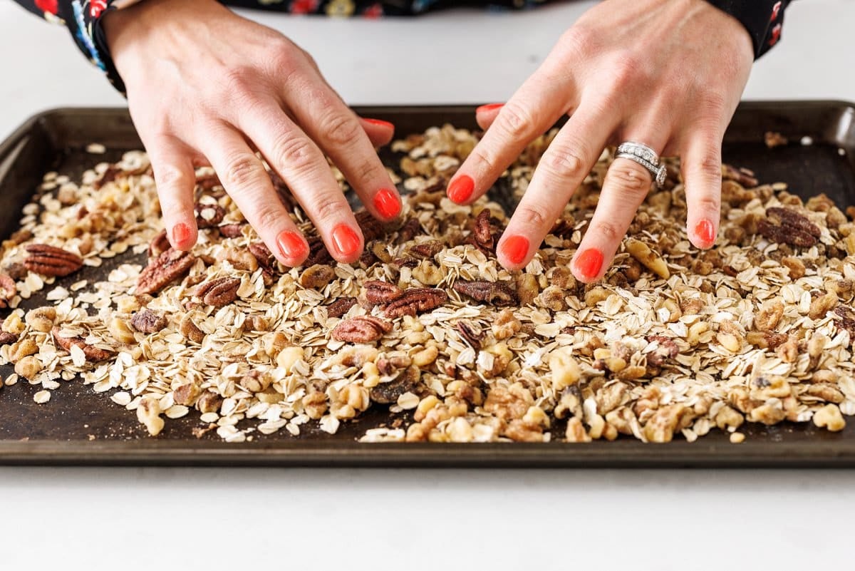 Spreading out oats and nuts on baking tray.