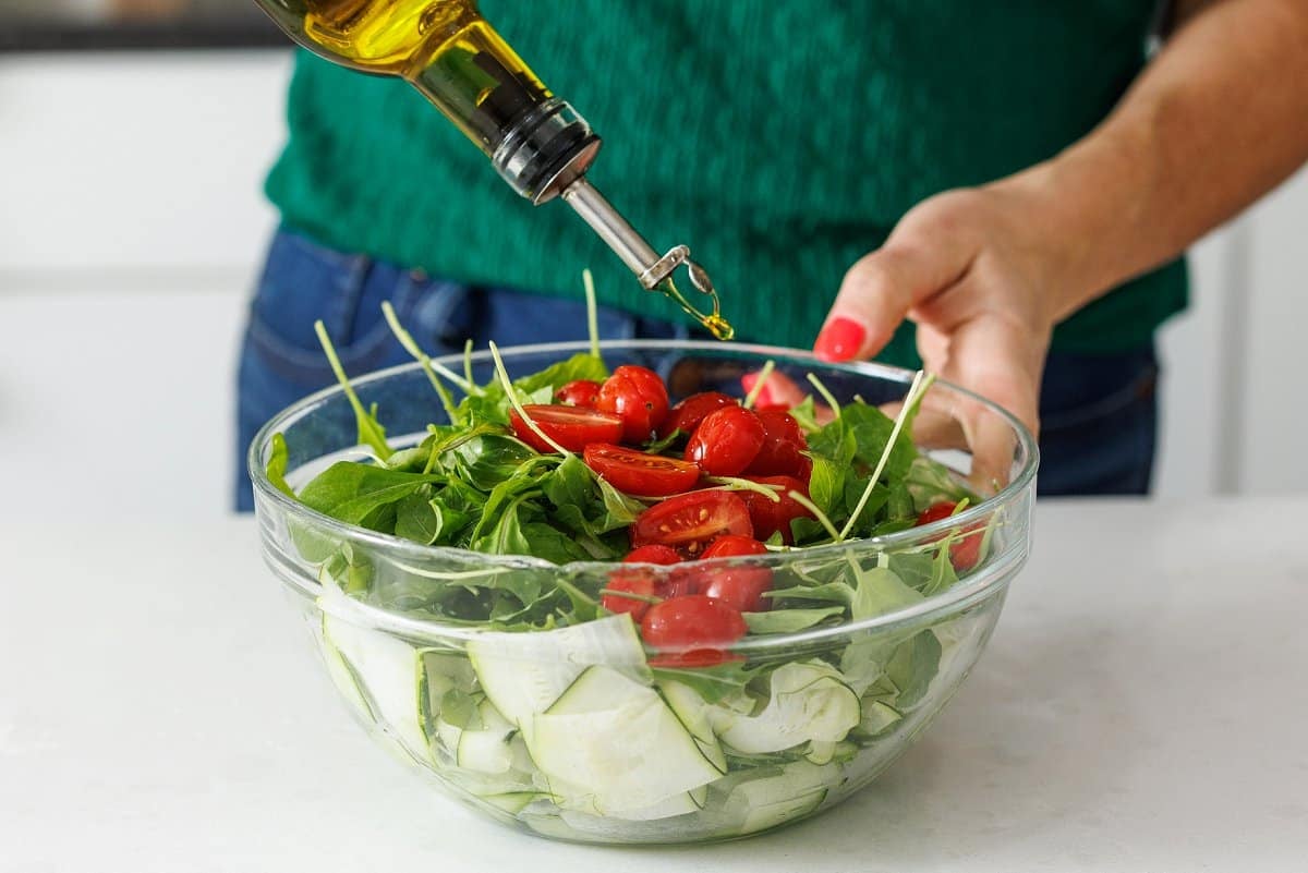 Drizzling olive oil over the top of a salad.