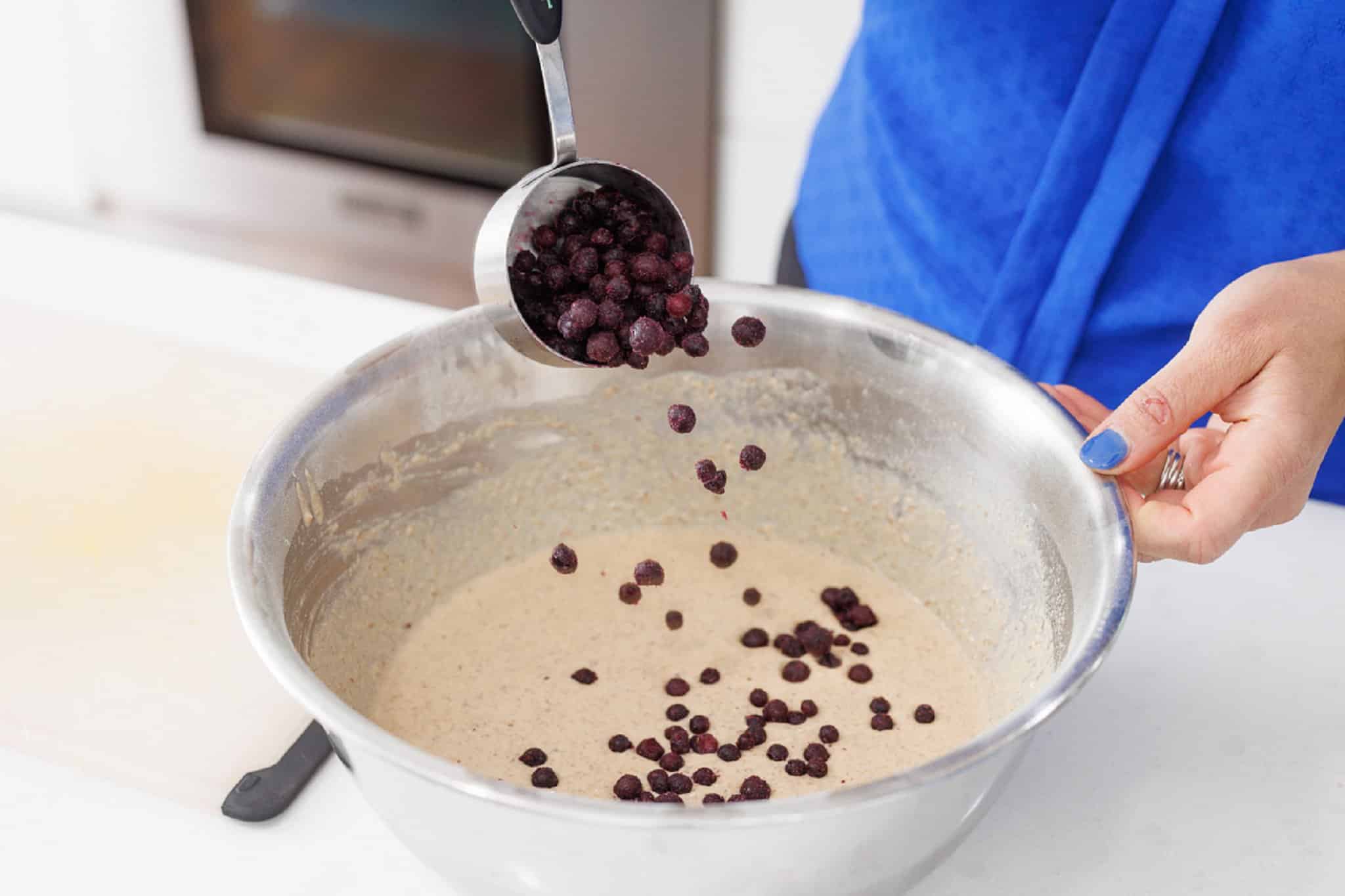 Stirring blueberries into waffle mix.