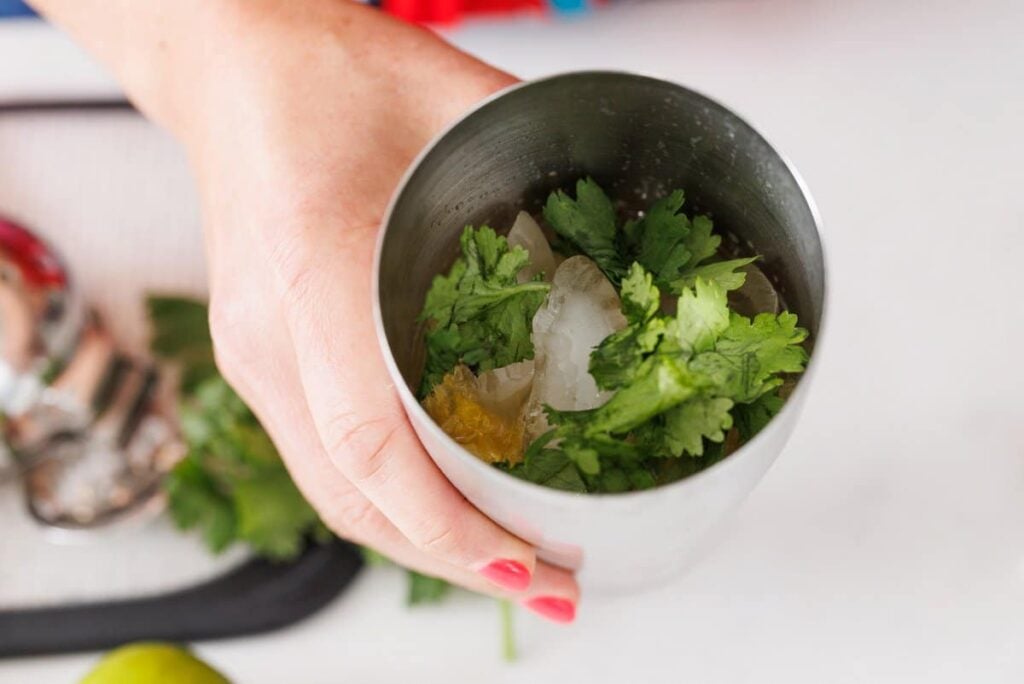Cilantro leaves added to cocktail shaker.