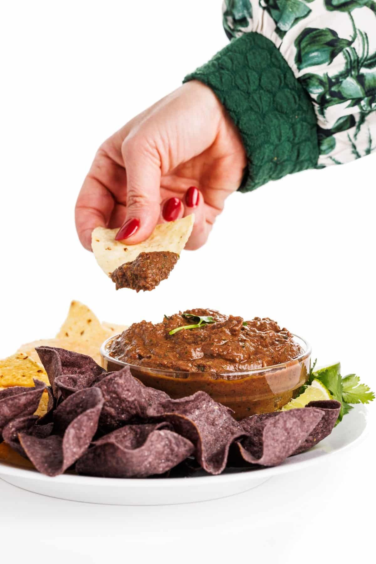 Dipping chips in black bean dip.