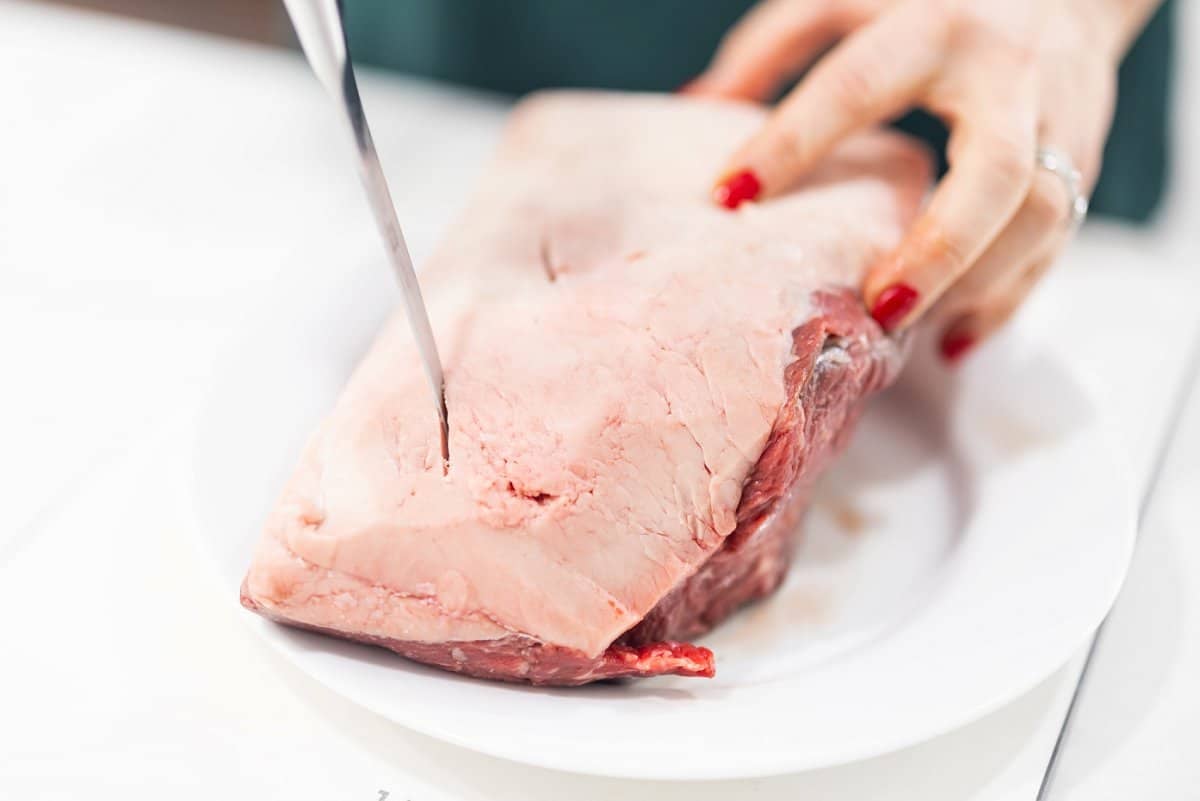Taking a sharp knife and cutting slits into strip roast.