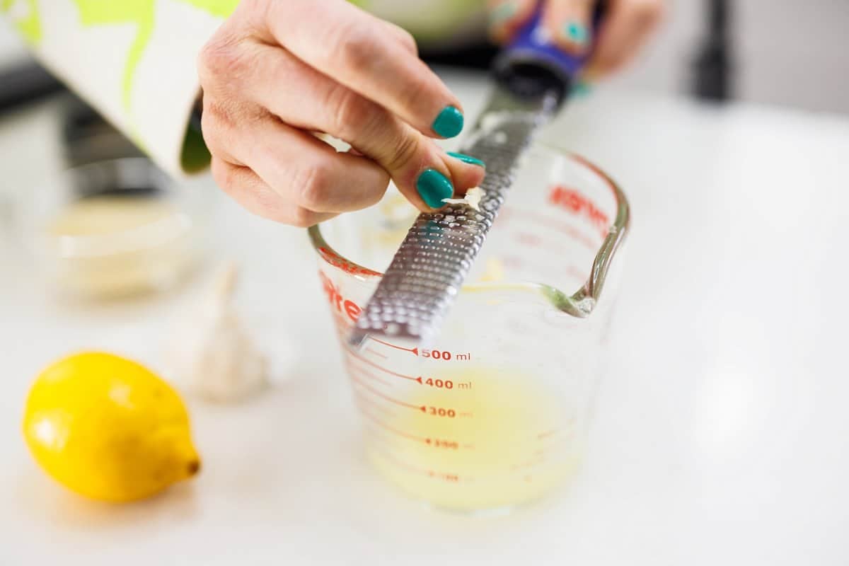 Using a microplane to grate garlic into measuring cup.