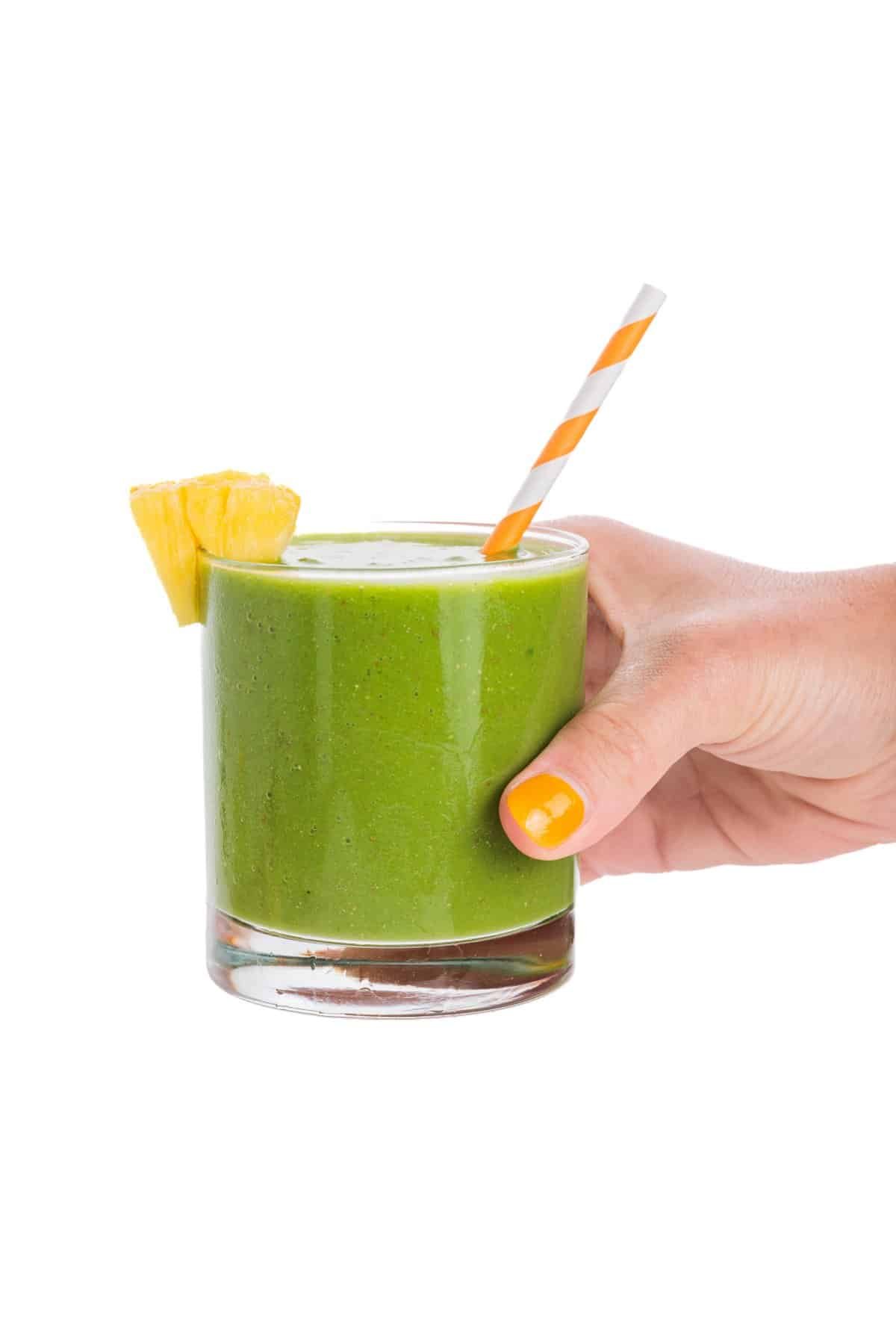 Holding a tropical green smoothie.