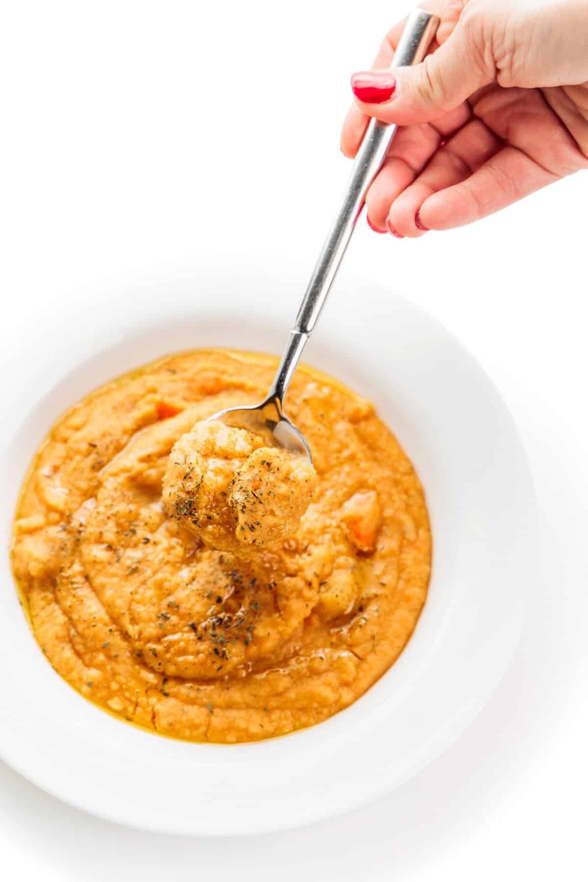 Spoonful of Turkish red lentil soup in a white bowl.